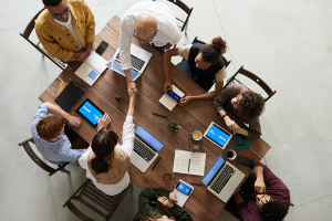 Group of people gathered in a table discussing and doing handshakes.