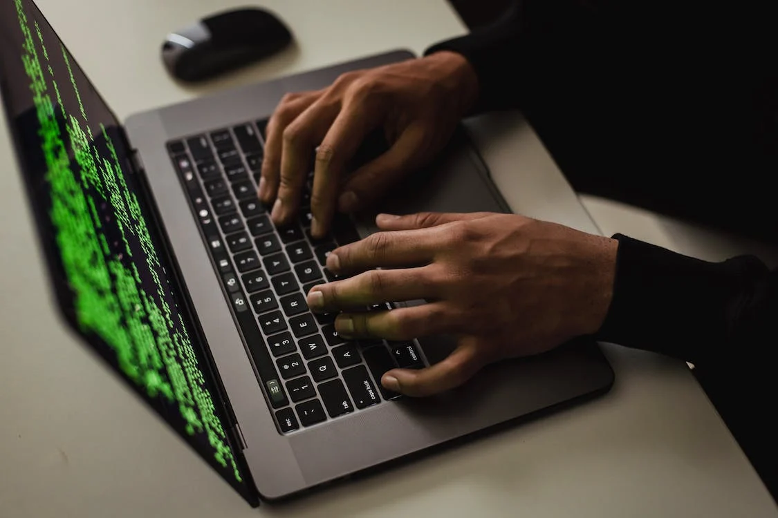 A hacker typing codes on a laptop.