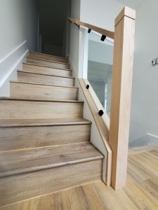 A wooden staircase with wooden railings and white walls.
