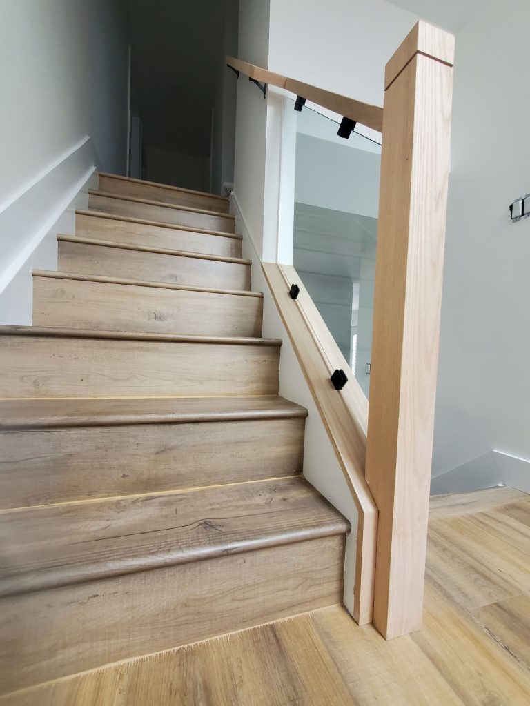 A wooden staircase with wooden railings and white walls.