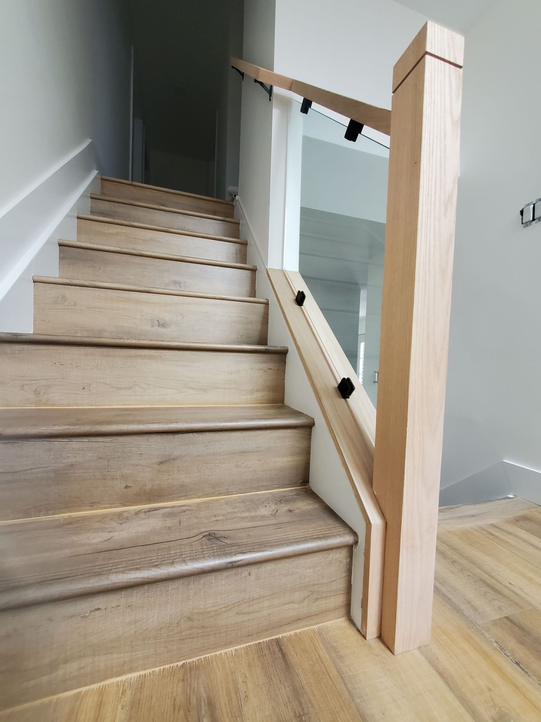 A wooden staircase with wooden railings and white walls.