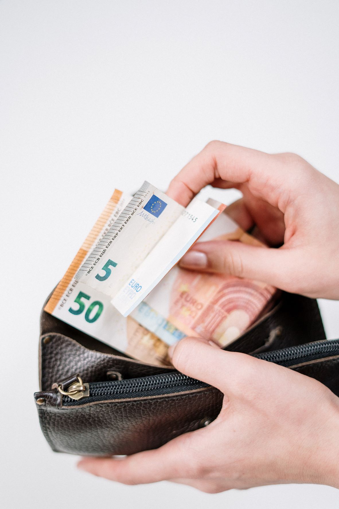 hand holding bills on a purse