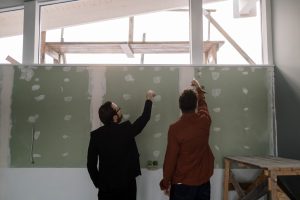 Two men pointing at the unfinished wall. Common Drywall Repair Issues