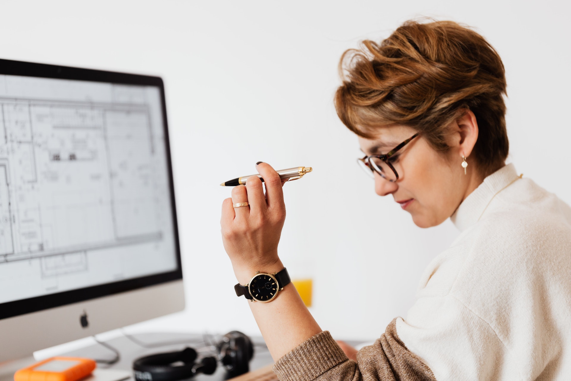 A woman holding a pen thinking in front of a computer Data management