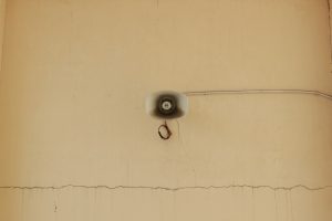 A megaphone mounted on a cracked wall.