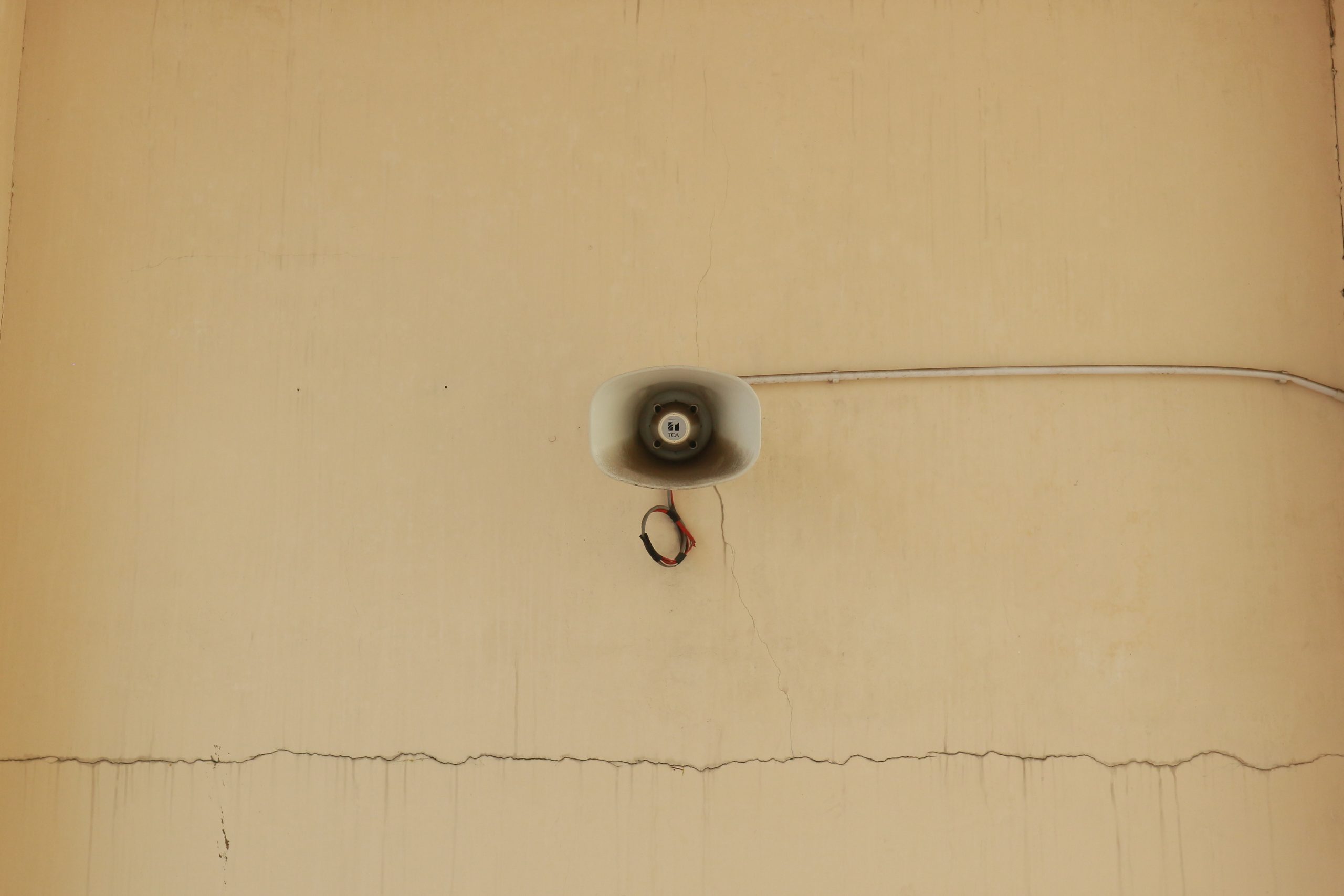 A megaphone mounted on a cracked wall.