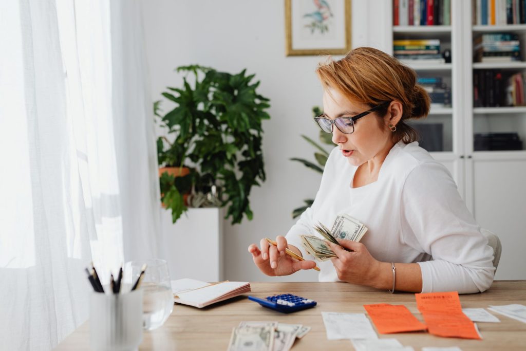 woman in white holding bills while calculating manage your money