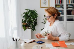 woman in white holding bills while calculating manage your money