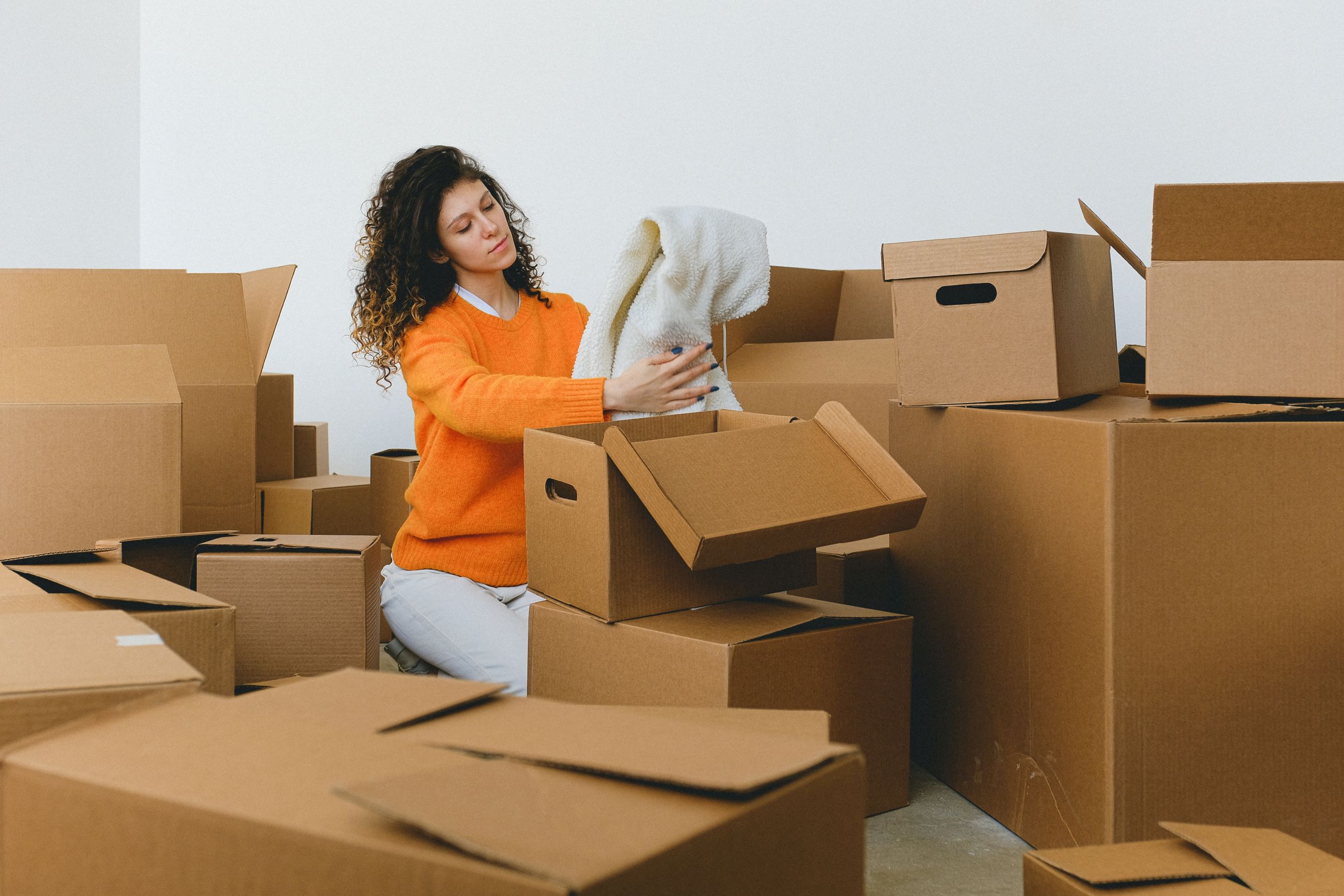 A woman decluttering and opening boxes in her room.