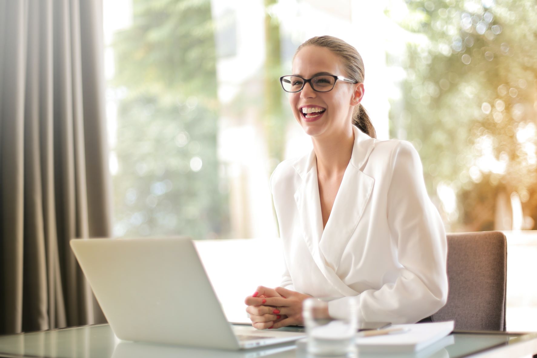 digital marketing content woman in white smiling with her laptop
