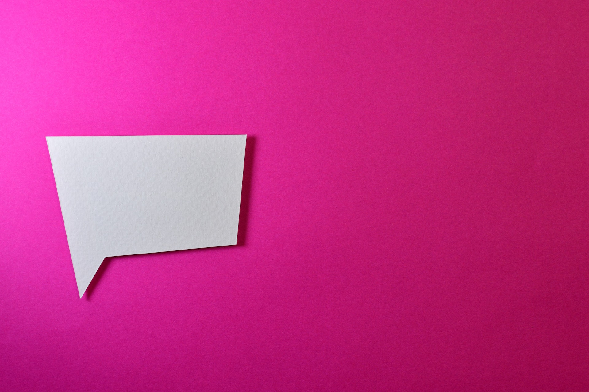 A white speech bubble on a pink background