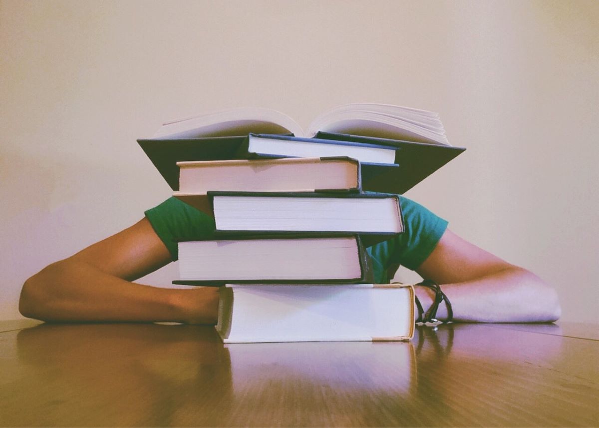woman behind stack of books paying off law school debt