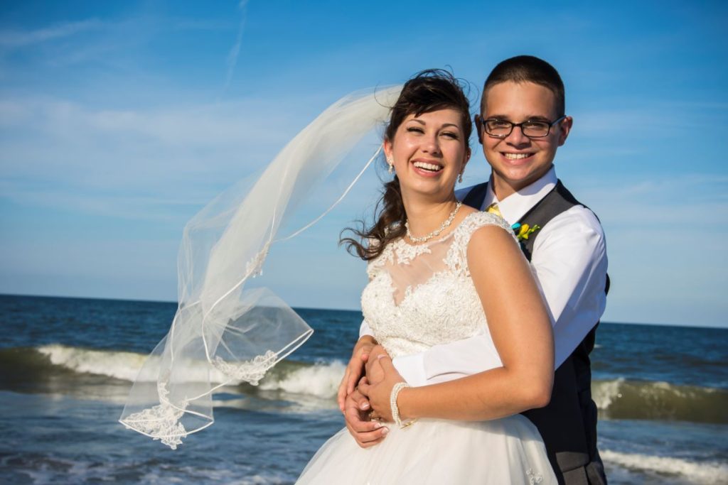 bride smiling as groom hugs her from behind being happy that they know the importance of wedding photography