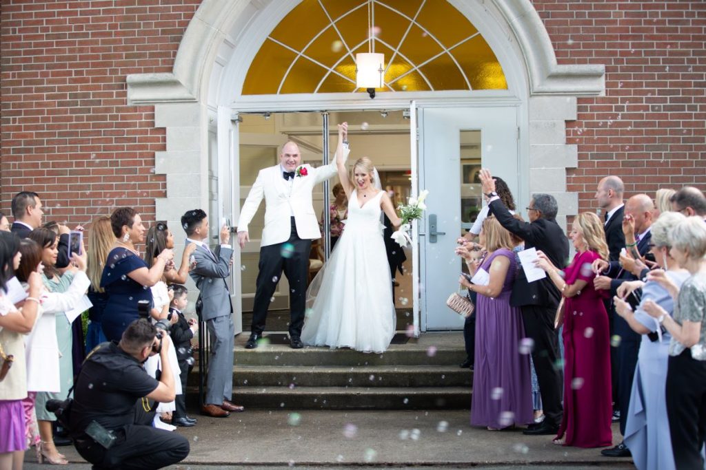 happy couple coming out of the church door celebrating their happiness as they enjoy the importance of wedding photography