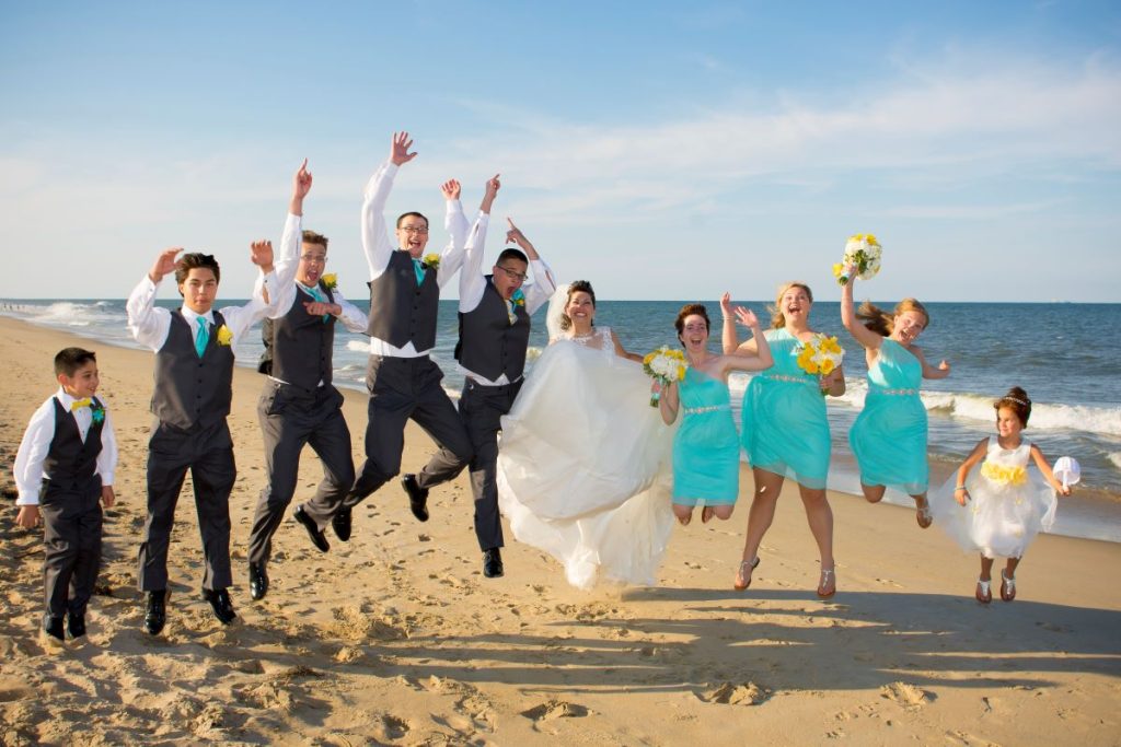 the groom and bride with their family jumping for a photo showing the importance of wedding photography