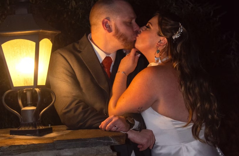 A married couple kissing in a dim lit room.